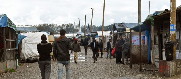 Migrants walks through the Jungle migrant camp in Calais, northern France, on October 22, 2016 - Sputnik International