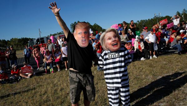 Craig Wendel dresses as Republican U.S. presidential nominee Donald Trump and his wife Jill Wendel wears a Hillary Clinton mask as they support Trump at a campaign rally in Naples, Florida, U.S. October 23, 2016 Craig Wendel dresses as Republican U.S. presidential nominee Donald Trump and his wife Jill Wendel wears a Hillary Clinton mask as they support Trump at a campaign rally in Naples, Florida, U.S. October 23, 2016 - Sputnik International