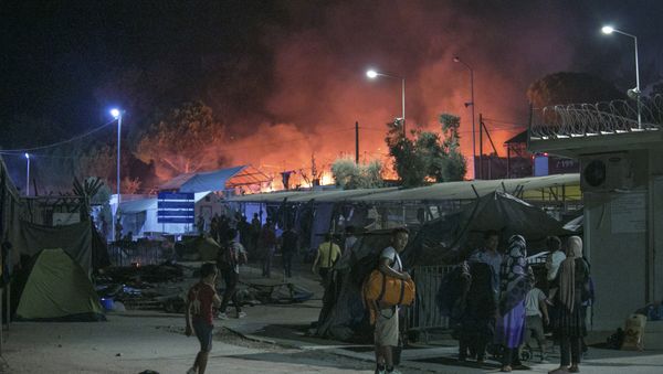 Migrants hold their belonging as a large fire burns inside the Moria refugee camp on the northeastern Greek island of Lesbos, late Monday, 19 September 2016 - Sputnik International