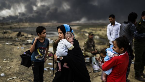 Iraqi families, who were displaced by the ongoing operation by Iraqi forces against jihadistds of the Islamic State group to retake the city of Mosul, are seen gathering on an area near Qayyarah on October 24, 2016 - Sputnik International
