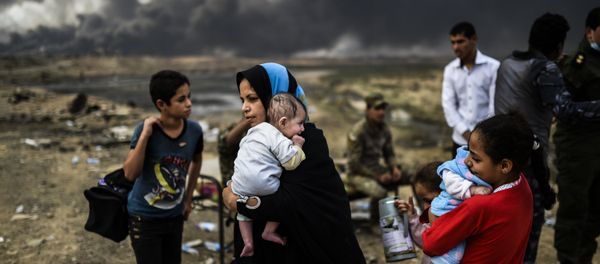 Iraqi families, who were displaced by the ongoing operation by Iraqi forces against jihadistds of the Islamic State group to retake the city of Mosul, are seen gathering on an area near Qayyarah on October 24, 2016 - Sputnik International