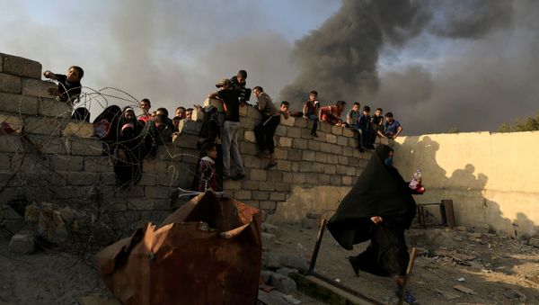 A newly displaced woman runs after she jumped over a back wall and rushed to grab humanitarian packages, as smoke rises from a burning oil refinery at a processing centre in Qayyara, south of Mosul, Iraq October 25, 2016 A newly displaced woman runs after she jumped over a back wall and rushed to grab humanitarian packages, as smoke rises from a burning oil refinery at a processing centre in Qayyara, south of Mosul, Iraq October 25, 2016 - Sputnik International