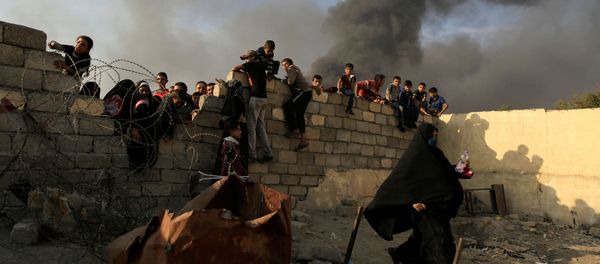 A newly displaced woman runs after she jumped over a back wall and rushed to grab humanitarian packages, as smoke rises from a burning oil refinery at a processing centre in Qayyara, south of Mosul, Iraq October 25, 2016 A newly displaced woman runs after she jumped over a back wall and rushed to grab humanitarian packages, as smoke rises from a burning oil refinery at a processing centre in Qayyara, south of Mosul, Iraq October 25, 2016 - Sputnik International