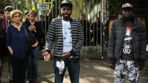 Sudanese refugees, who said their names are Adam, center, and Anour, right, speak to media in front of the entrance of the occupied Gerhart Hauptmann School in Berlin, Germany, Friday, June 27, 2014 - Sputnik International