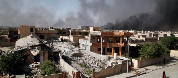 People walk along a street as smoke rises near Qayyarah, south of Mosul, Iraq - Sputnik International