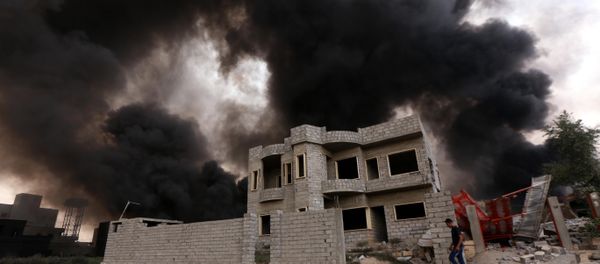 An Iraqi man walks near smoke billowing An Iraqi man walks near smoke billowing - Sputnik International