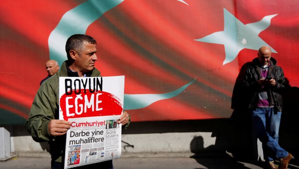A supporter of Cumhuriyet newspaper, an opposition secularist daily, holds a placard and the latest copy during a protest in front of its headquarters in Istanbul, Turkey, October 31, 2016. The placard reads, Don't bow down. - Sputnik International