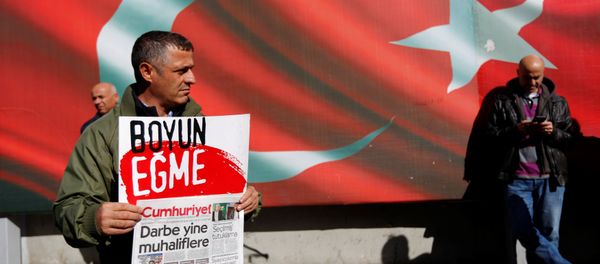 A supporter of Cumhuriyet newspaper, an opposition secularist daily, holds a placard and the latest copy during a protest in front of its headquarters in Istanbul, Turkey, October 31, 2016. The placard reads, Don't bow down. - Sputnik International
