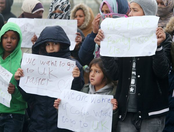 Young migrants pose with posters reading 'We want to go faster to UK' and 'We have family waiting for us' at the Jungle migrant camp in Calais, northern France, on October 26, 2016. - Sputnik International