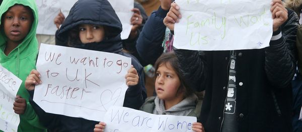 Young migrants pose with posters reading 'We want to go faster to UK' and 'We have family waiting for us' at the Jungle migrant camp in Calais, northern France, on October 26, 2016. - Sputnik International