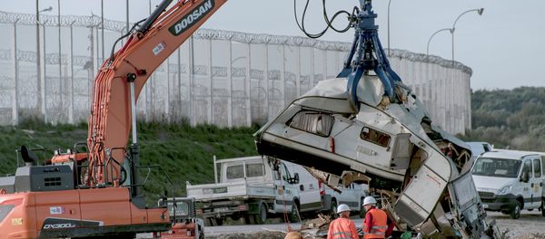Workers watch as a crane destroys a caravan, once used as a makeshift shelter, at the site of the 'Jungle' migrant camp, on October 31, 2016 in Calais, northern France, as a massive operation to clear the settlement nears completion Workers watch as a crane destroys a caravan, once used as a makeshift shelter, at the site of the 'Jungle' migrant camp, on October 31, 2016 in Calais, northern France, as a massive operation to clear the settlement nears completion - Sputnik International
