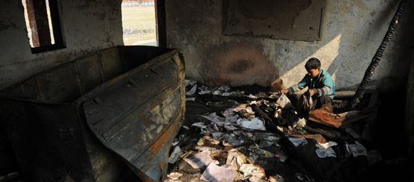 A Kashmiri student looks at damaged property at a partially burnt government high school in Goripora, on the outskirts of Srinagar on November 2, 2016 - Sputnik International