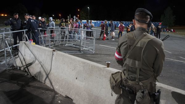 An Austrian Army soldier stands guard migrants lining up to get on a bus after they arrived at the border between Austria and Hungary near Heiligenkreuz, about 180 kms (110 miles) south of Vienna, Austria, Friday, Sept. 18, 2015 - Sputnik International