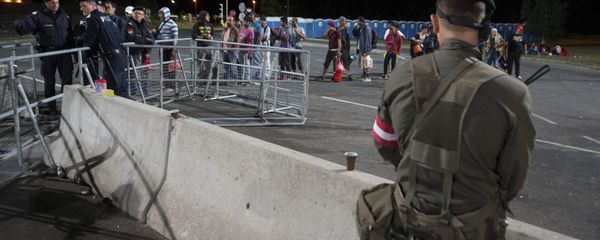 An Austrian Army soldier stands guard migrants lining up to get on a bus after they arrived at the border between Austria and Hungary near Heiligenkreuz, about 180 kms (110 miles) south of Vienna, Austria, Friday, Sept. 18, 2015 - Sputnik International