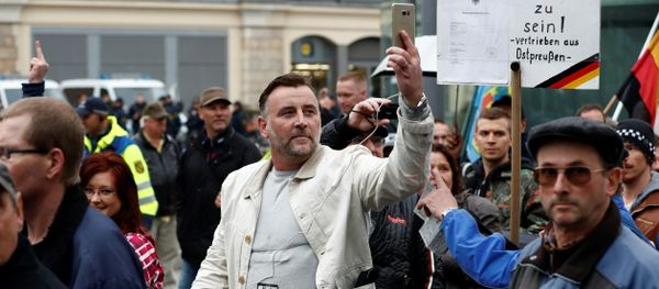 Lutz Bachmann (C), co-founder of the Pegida movement (Patriotic Europeans Against the Islamisation of the Occident), documents with his mobile phone as he takes part in a protest against German Chancellor Angela Merkel and her policy, on October 3, 2016, the German Unity Day, in Dresden, eastern Germany Lutz Bachmann (C), co-founder of the Pegida movement (Patriotic Europeans Against the Islamisation of the Occident), documents with his mobile phone as he takes part in a protest against German Chancellor Angela Merkel and her policy, on October 3, 2016, the German Unity Day, in Dresden, eastern Germany - Sputnik International