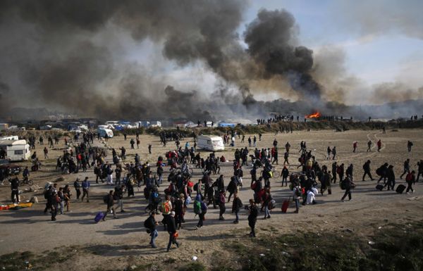Oct. 26, 2016 file photo people walk past as thick smoke and flames rise from amidst the tents after fires were started in the makeshift migrant camp known as the jungle near Calais, northern France. Oct. 26, 2016 file photo people walk past as thick smoke and flames rise from amidst the tents after fires were started in the makeshift migrant camp known as the jungle near Calais, northern France. - Sputnik International