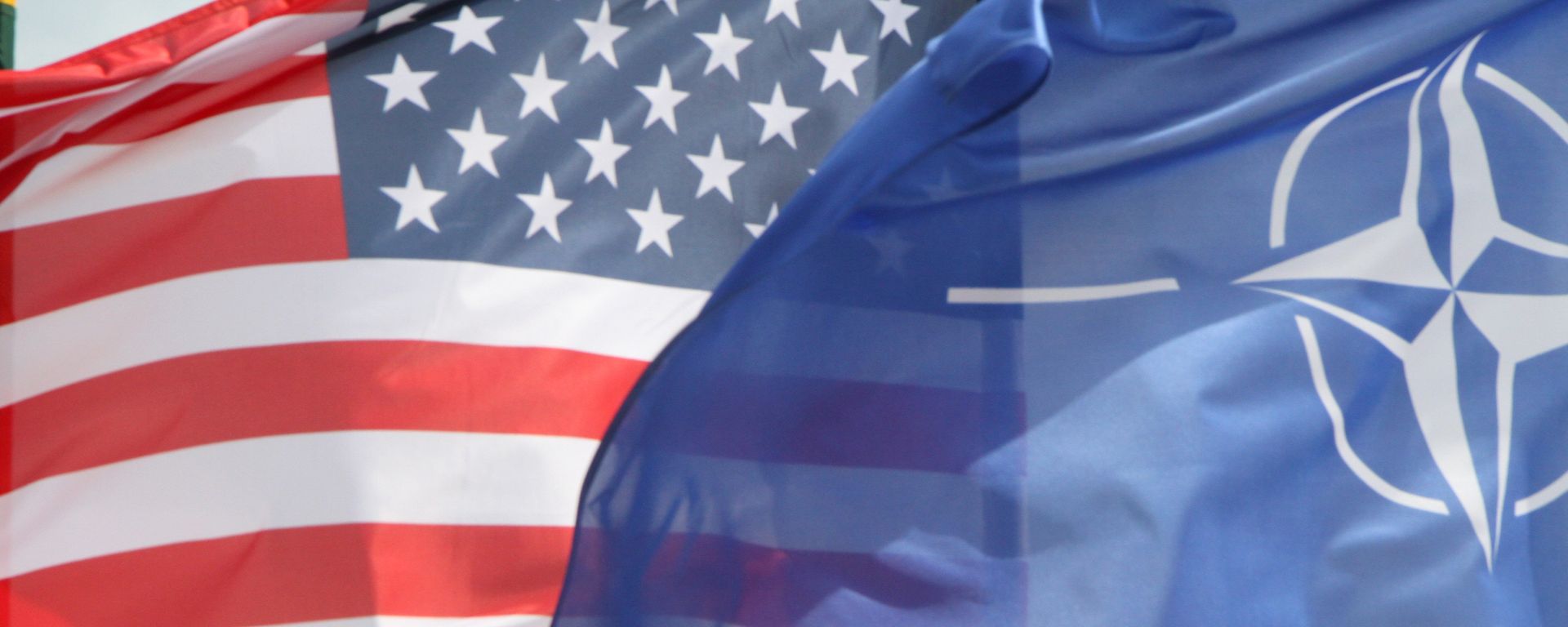 The US and The NATO flag flie in front of two US Air Force F-22 Raptor fighter aircrafts at the Air Base of the Lithuanian Armed Forces in Šiauliai, Lithuania, on April 27, 2016.  - Sputnik International, 1920, 19.01.2026