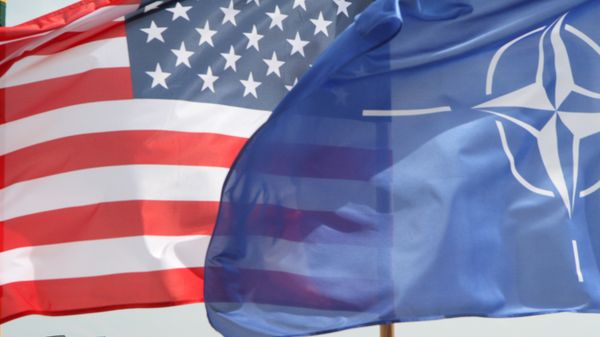 The US and The NATO flag flie in front of two US Air Force F-22 Raptor fighter aircrafts at the Air Base of the Lithuanian Armed Forces in Šiauliai, Lithuania, on April 27, 2016. - Sputnik International