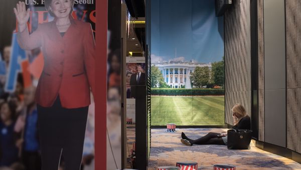 A woman sits on the floor behind a cut-outs of US presidential nominees Hillary Clinton and Donald Trump at an election event organised by the US embassy, at a hotel in Seoul on November 9, 2016 - Sputnik International