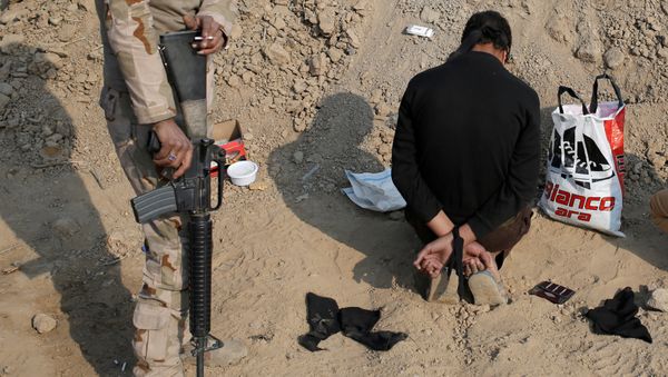 An Iraqi soldier stands next to a detained man accused of being an Islamic State fighter, at a check point in Qayyara, south of Mosul, Iraq October 27, 2016 - Sputnik International
