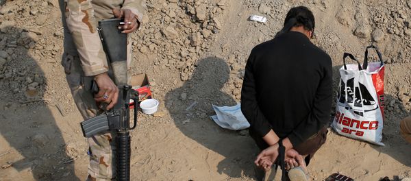 An Iraqi soldier stands next to a detained man accused of being an Islamic State fighter, at a check point in Qayyara, south of Mosul, Iraq October 27, 2016 - Sputnik International