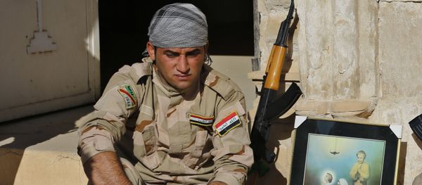 Iraqi Christian soldiers from the Nineveh Plain Protection Unit, sit next to a poster showing the Virgin Mary and Jesus Christ outside St. Addai church which was damaged by Islamic State fighters during their occupation of Keramlis village, less than 18 miles, 29 kilometers, southeast of Mosul, Iraq, Sunday Nov. 13, 2016 - Sputnik International