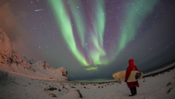 A surfer looks at northern lights ( aurora borealis ) at the snow covered beach of Unstad, on Lofoten Island, Arctic Circle, on March 9, 2016 A surfer looks at northern lights ( aurora borealis ) at the snow covered beach of Unstad, on Lofoten Island, Arctic Circle, on March 9, 2016 - Sputnik International