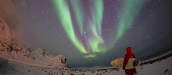 A surfer looks at northern lights ( aurora borealis ) at the snow covered beach of Unstad, on Lofoten Island, Arctic Circle, on March 9, 2016 A surfer looks at northern lights ( aurora borealis ) at the snow covered beach of Unstad, on Lofoten Island, Arctic Circle, on March 9, 2016 - Sputnik International