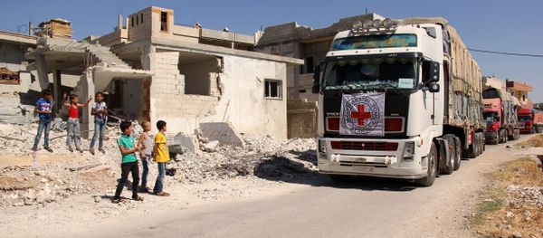 Syrian children stand on the side of a road watching a 48-truck convoy from the ICRC, SARC and UN driving through the Syrian rebel-held village of Teir Maalah, on the northern outskirts of Homs in central Syria, as it heads to the besieged town of Talbisseh on July 26, 2016 - Sputnik International