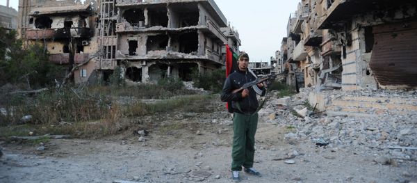 In this Feb. 23, 2016 file photo, a civilian fighter holding the Libyan flag stands in front of damaged buildings in Benghazi, Libya In this Feb. 23, 2016 file photo, a civilian fighter holding the Libyan flag stands in front of damaged buildings in Benghazi, Libya - Sputnik International