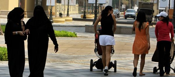 Foreign women walk past fully-veiled local women in the Gulf emirate of Dubai on September 15, 2010. - Sputnik International