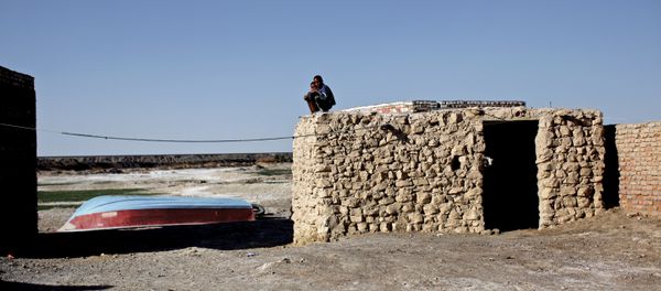 Iranian boys sit on the roof of a mud-house in Adimi village in Hamoon wetland near the Zabol town in southeastern province of Sistan-Baluchistan bordering Afghanistan on February 2, 2015. - Sputnik International