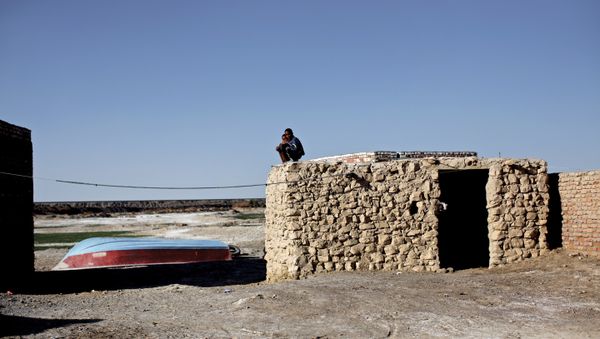 Iranian boys sit on the roof of a mud-house in Adimi village in Hamoon wetland near the Zabol town in southeastern province of Sistan-Baluchistan bordering Afghanistan on February 2, 2015. - Sputnik International