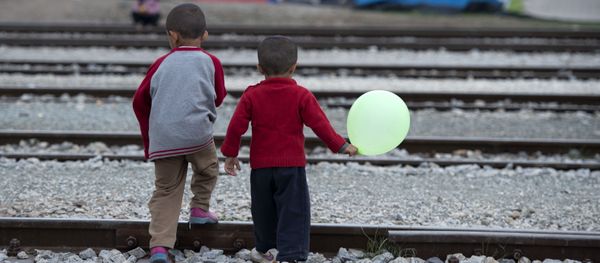 Children cross rail tracks at a makeshift camp for migrants and refugees near the village of Idomeni not far from the Greek-Macedonian border - Sputnik International