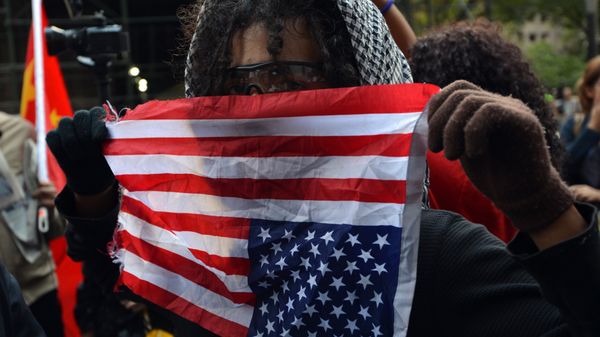 An Occupy Wall Street protester holds an American flag upside down as a sign of distress near Wall Street September 17, 2012 on the one year anniversary of the movement in New York - Sputnik International