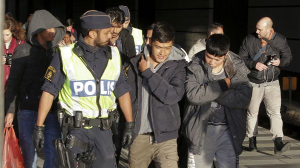 A group of migrants who have deboarded a train walk down a platform accompanied by police at the Swedish end of the bridge between Sweden and Denmark near Malmo on 12 November 2015. - Sputnik International