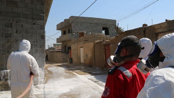 Members of the civil defence spray and clean areas in the town of Taza, around 220 kilometres north of the capital Baghdad. (File) - Sputnik International