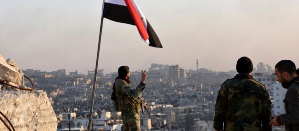A Syrian government soldier gestures a v-sign under the Syrian national flag near a general view of eastern Aleppo after they took control of al-Sakhour neigbourhood in Aleppo, Syria in this handout picture provided by SANA on November 28, 2016. - Sputnik International