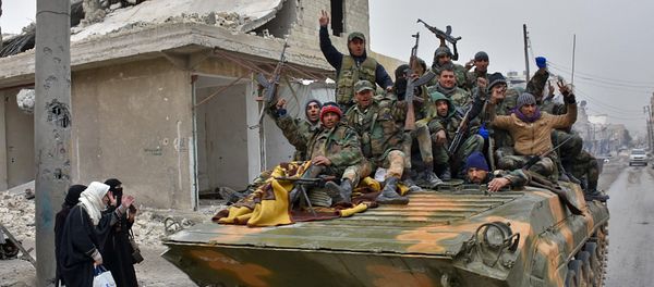 Syrian pro-government forces sit on a military vehicle driving past residents fleeing the eastern part of Aleppo and gathering in Masaken Hanano, a former rebel-held district which was retaken by the regime forces last week, on November 30, 2016. - Sputnik International