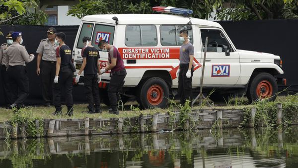 Indonesian police officers stand near an ambulance used to carry the bodies of the victims of a plane crash outside the morgue at the police hospital in Surabaya, East Java, Indonesia (File) - Sputnik International