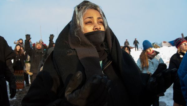 A woman watches the sunrise in Oceti Sakowin camp as water protectors continue to demonstrate against plans to pass the Dakota Access pipeline near the Standing Rock Indian Reservation, near Cannon Ball, North Dakota, U.S. December 3, 2016 - Sputnik International
