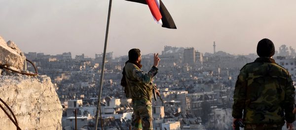 A Syrian government soldier gestures a v-sign under the Syrian national flag near a general view of eastern Aleppo after they took control of al-Sakhour neigbourhood in Aleppo, Syria in this handout picture provided by SANA on November 28, 2016 A Syrian government soldier gestures a v-sign under the Syrian national flag near a general view of eastern Aleppo after they took control of al-Sakhour neigbourhood in Aleppo, Syria in this handout picture provided by SANA on November 28, 2016 - Sputnik International