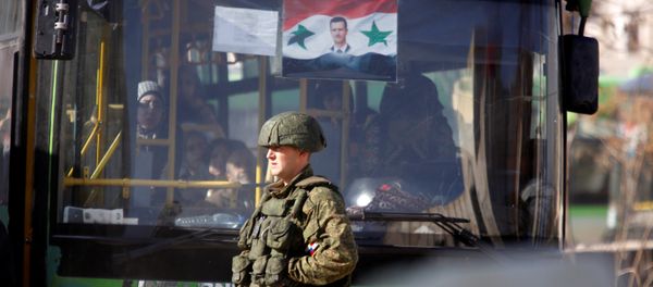A Russian soldier stands near a bus carrying people who came back to inspect their homes in government controlled Hanono housing district in Aleppo, Syria December 4, 2016 - Sputnik International