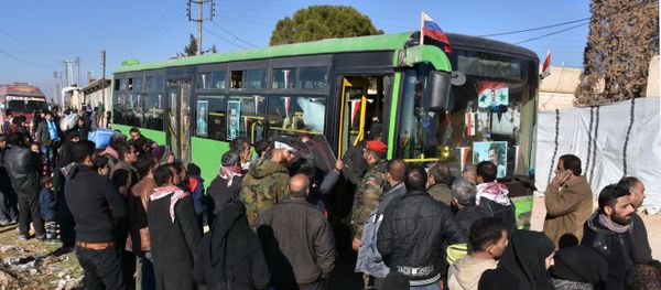 Syrian residents fleeing the violence, queue as they board a bus at a checkpoint, manned by pro-government forces, in the village of Aziza on the southwestern outskirts of the northern Syrian city of Aleppo on December 9, 2016 - Sputnik International