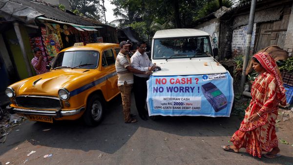 A bank officer swipes an ATM card of a man withdrawing Indian rupee banknotes at a mobile ATM van on the outskirts of Kolkata, India, November 24, 2016 A bank officer swipes an ATM card of a man withdrawing Indian rupee banknotes at a mobile ATM van on the outskirts of Kolkata, India, November 24, 2016 - Sputnik International