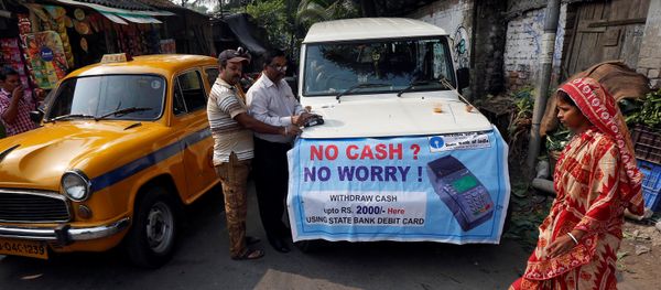 A bank officer swipes an ATM card of a man withdrawing Indian rupee banknotes at a mobile ATM van on the outskirts of Kolkata, India, November 24, 2016 - Sputnik International