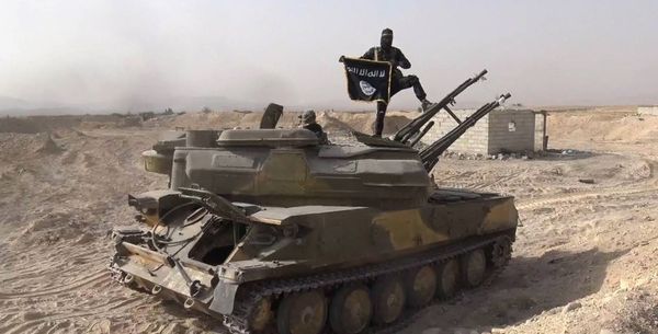 In this file photo released on Aug. 5, 2015, by the Rased News Network a Facebook page affiliated with Islamic State militants, an Islamic State militant holds the group's flag as he stands on a tank they captured from Syrian government forces, in the town of Qaryatain southwest of Palmyra, central Syria - Sputnik International