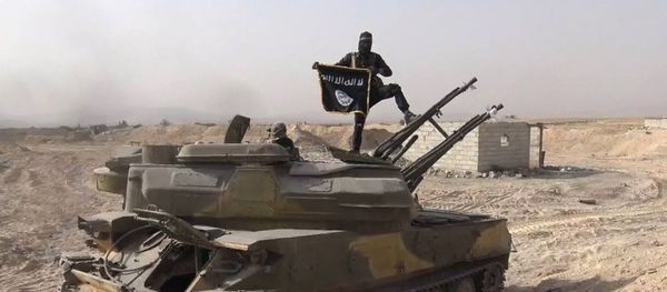 In this file photo released on Aug. 5, 2015, by the Rased News Network a Facebook page affiliated with Islamic State militants, an Islamic State militant holds the group's flag as he stands on a tank they captured from Syrian government forces, in the town of Qaryatain southwest of Palmyra, central Syria In this file photo released on Aug. 5, 2015, by the Rased News Network a Facebook page affiliated with Islamic State militants, an Islamic State militant holds the group's flag as he stands on a tank they captured from Syrian government forces, in the town of Qaryatain southwest of Palmyra, central Syria - Sputnik International