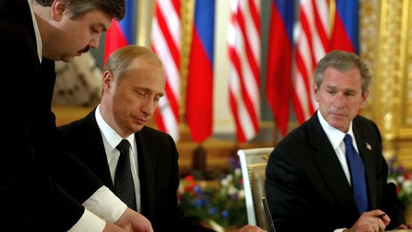 US President George W. Bush (R) looks on as Russian President Vladimir Putin (C) signs 24 May 2002 in St. Catherine's Room, the Kremlin in Moscow, Russia what the White House calls the Treaty of Moscow, a 10-year treaty binding the nations to reduce their nuclear stockpiles by about two-thirds - to a range of 1,700 to 2,200 - Sputnik International