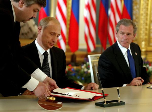 US President George W. Bush (R) looks on as Russian President Vladimir Putin (C) signs 24 May 2002 in St. Catherine's Room, the Kremlin in Moscow, Russia what the White House calls the Treaty of Moscow, a 10-year treaty binding the nations to reduce their nuclear stockpiles by about two-thirds - to a range of 1,700 to 2,200 - Sputnik International